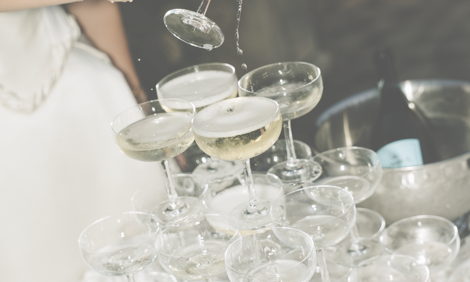A pyramid of champagne glasses being filled with champagne